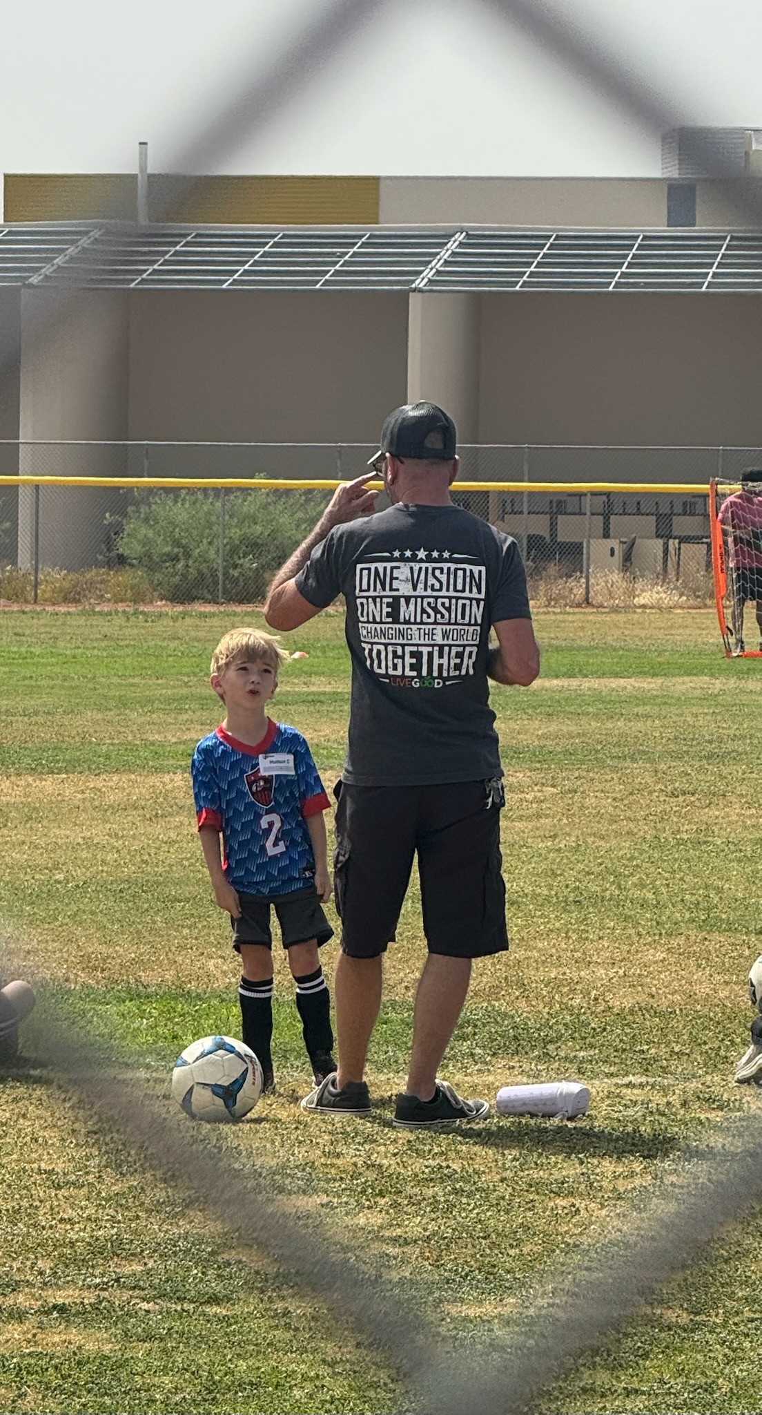 Jason Chamberlin wearing a LiveGood shirt while Hudson looks up at him on the soccer field
